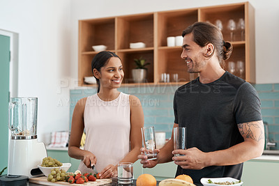 Buy stock photo Cropped shot of an affectionate young couple making smoothies in their kitchen at home