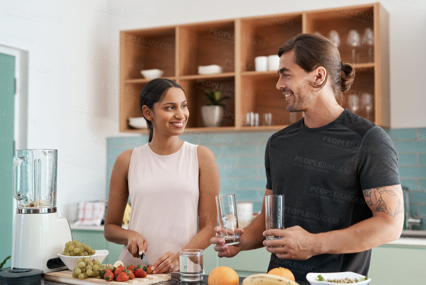 Buy stock photo Cropped shot of an affectionate young couple making smoothies in their kitchen at home