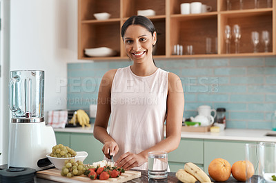 Buy stock photo Cropped portrait of an attractive young woman making smoothies in her kitchen at home