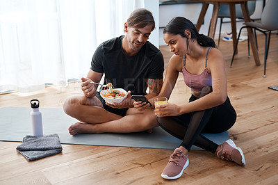 Buy stock photo Full length shot of an athletic young couple enjoying some healthy snacks after their workout at home