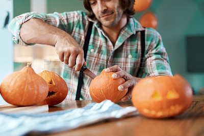 Buy stock photo Shot of a young man carving a pumpkin at home