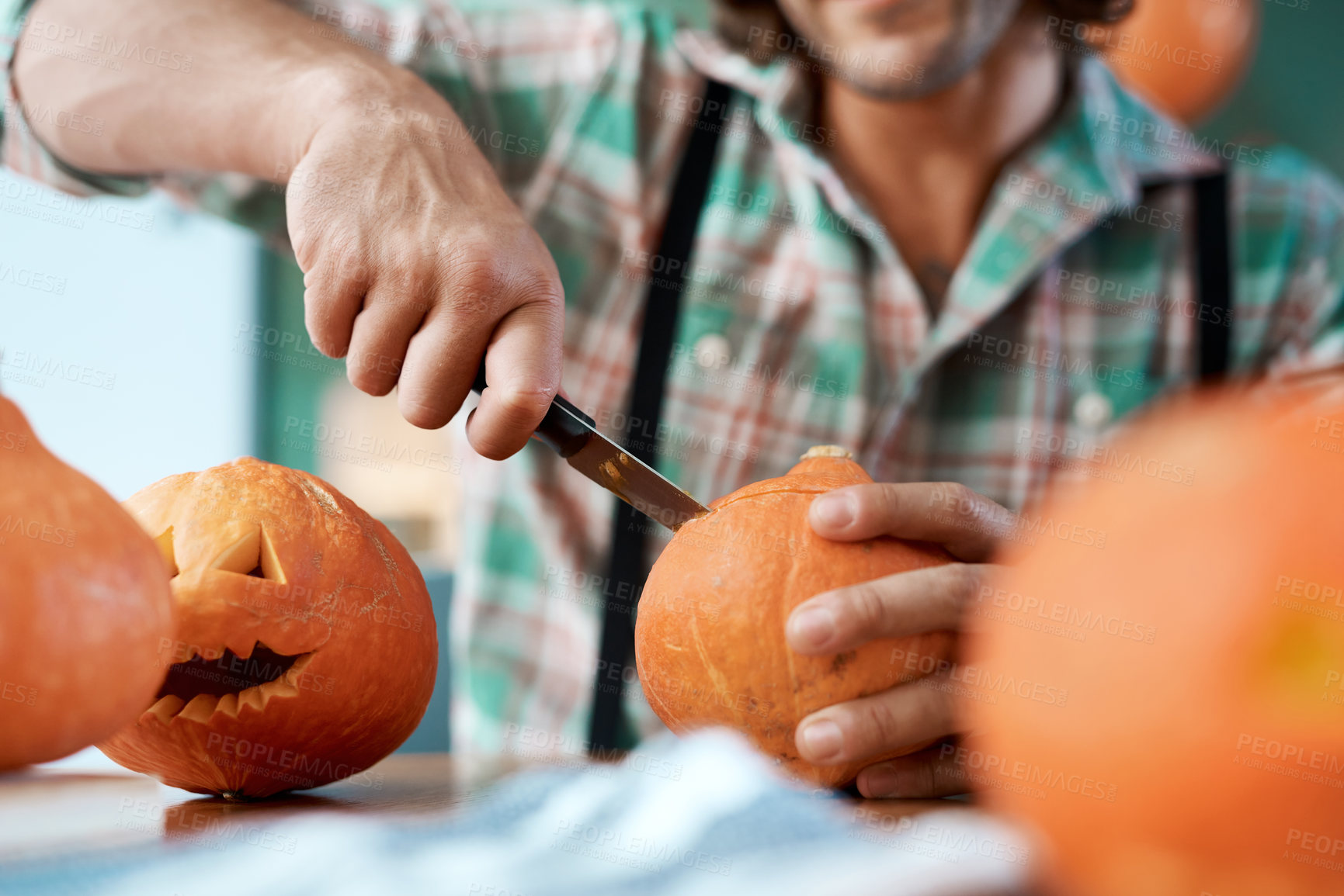 Buy stock photo Shot of a young man carving a pumpkin at home