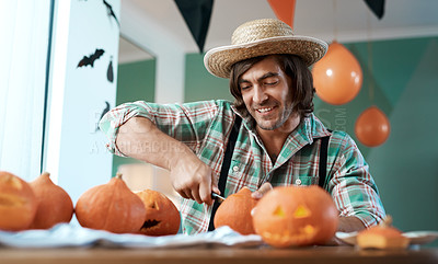 Buy stock photo Shot of a young man carving a pumpkin at home