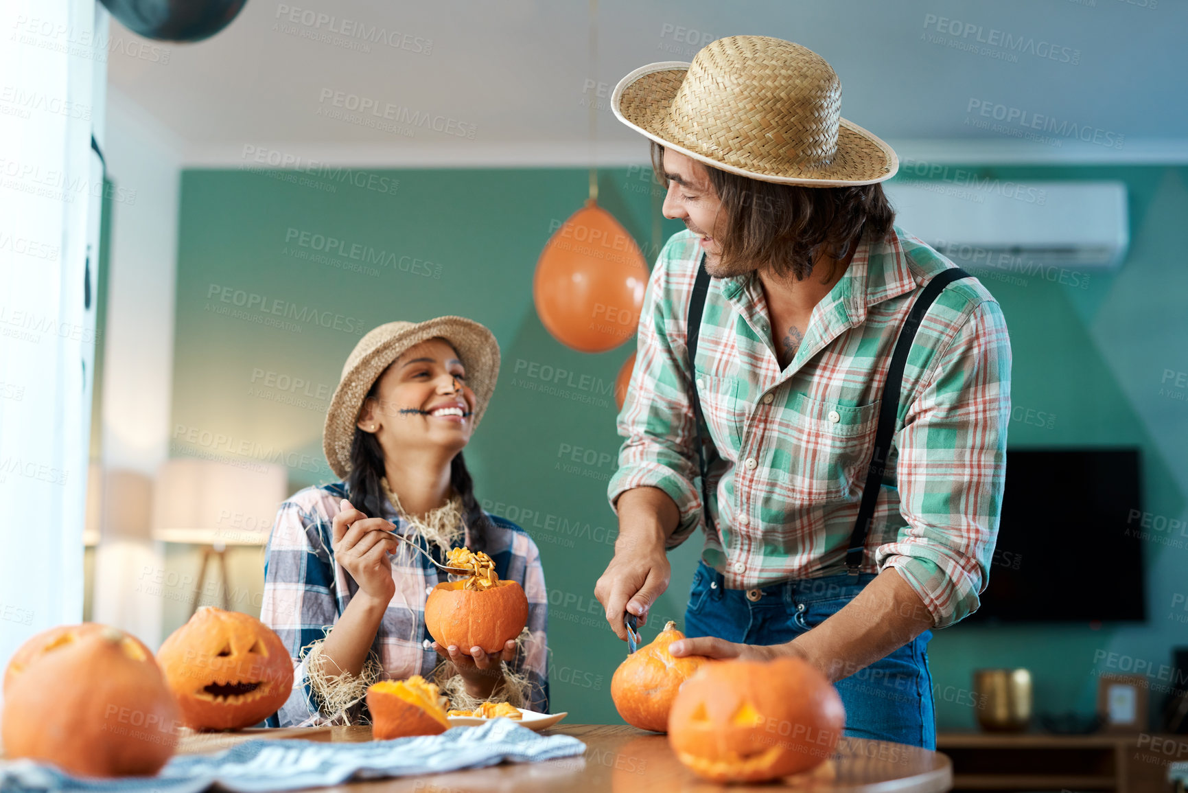 Buy stock photo Shot of a young couple carving pumpkins at home