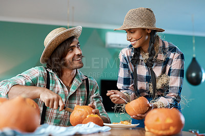 Buy stock photo Shot of a young couple carving pumpkins at home