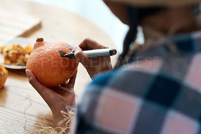 Buy stock photo Shot of an unrecognizable person drawing on a pumpkin at home