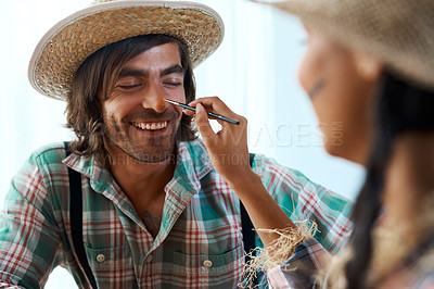 Buy stock photo Shot of a young woman applying makeup to a young man at home