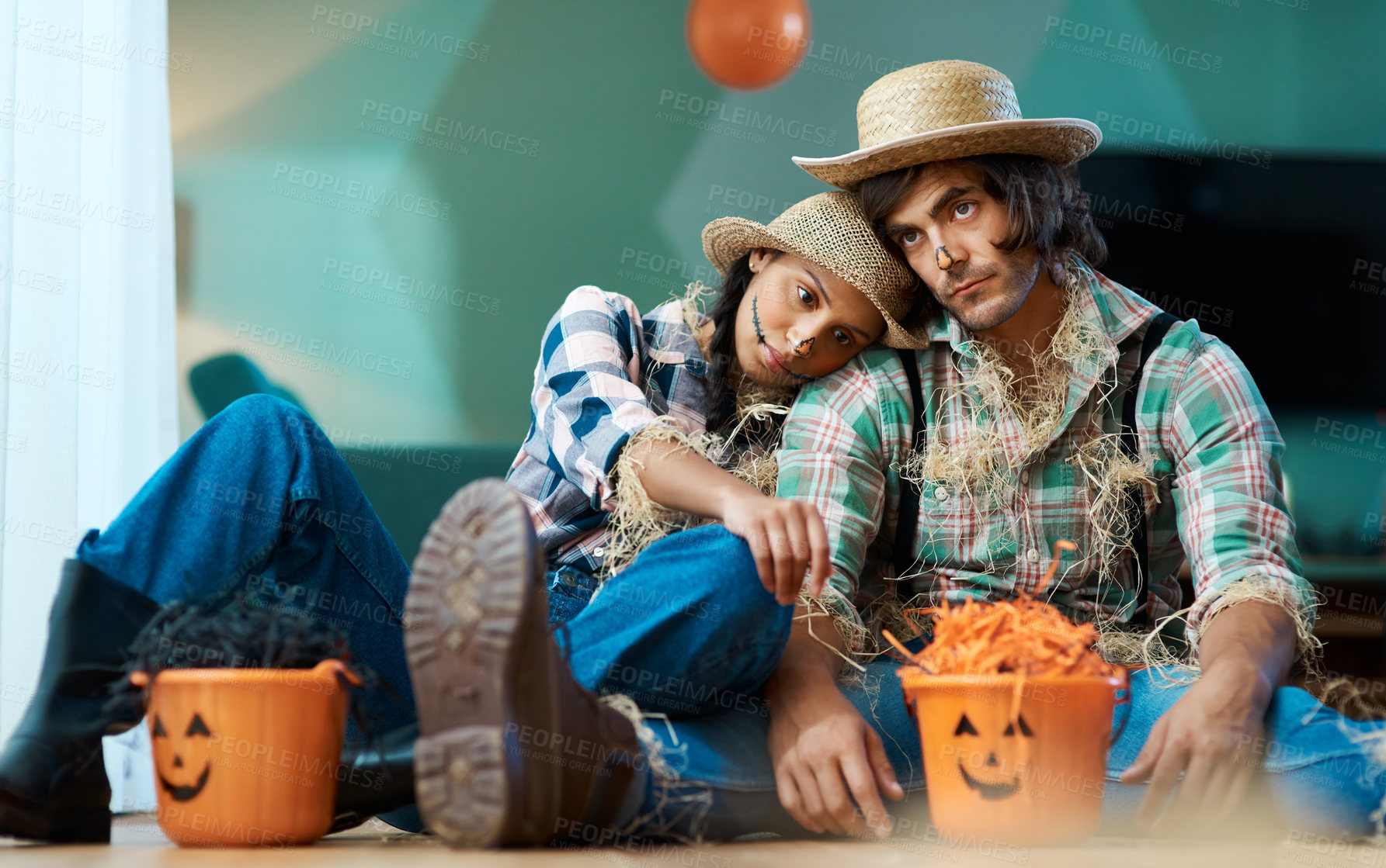 Buy stock photo Shot of a young couple dressed in halloween costumes looking sad at home
