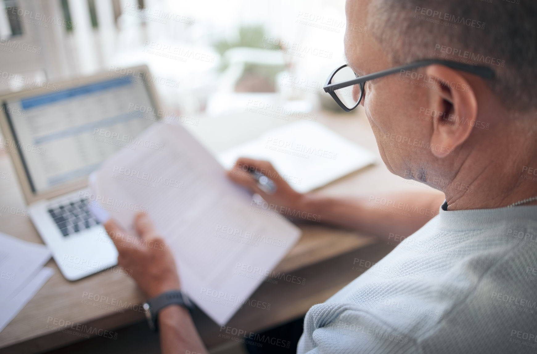 Buy stock photo Shot of a mature man reading over financial documents while working