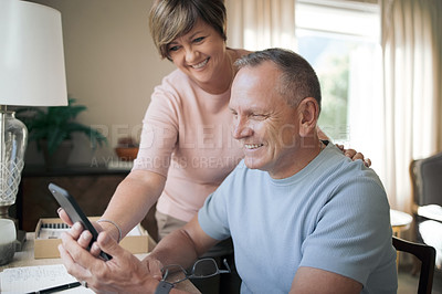 Buy stock photo Shot of a mature husband and wife together using a smartphone