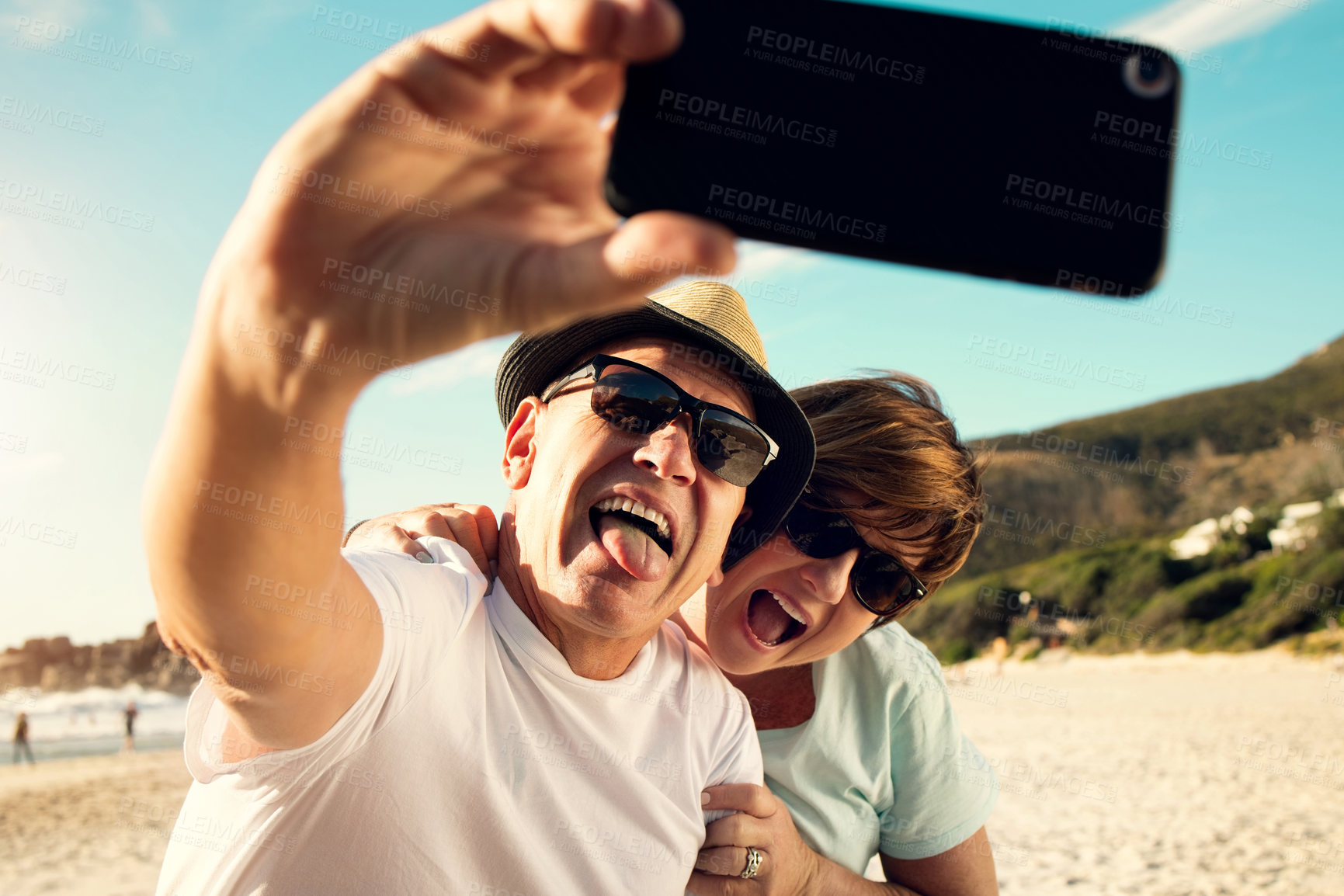 Buy stock photo Shot of a mature couple taking a selfie while spending the day at the beach