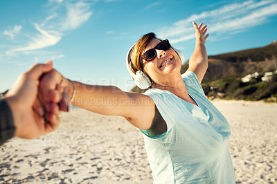 Buy stock photo Shot of a woman wearing headphones and enjoying herself at the beach