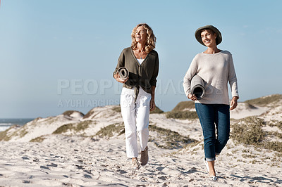 Buy stock photo Full length shot of two attractive mature woman walking with their on the beach