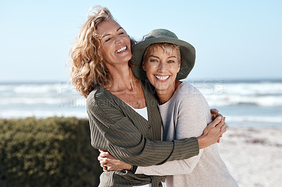 Buy stock photo Cropped shot of two attractive mature women hugging while standing on the beach