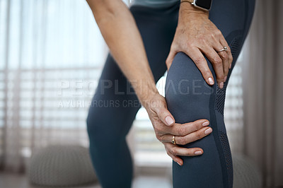 Buy stock photo Cropped closeup of an unrecognizable woman experiencing pain in her knee while exercising at home