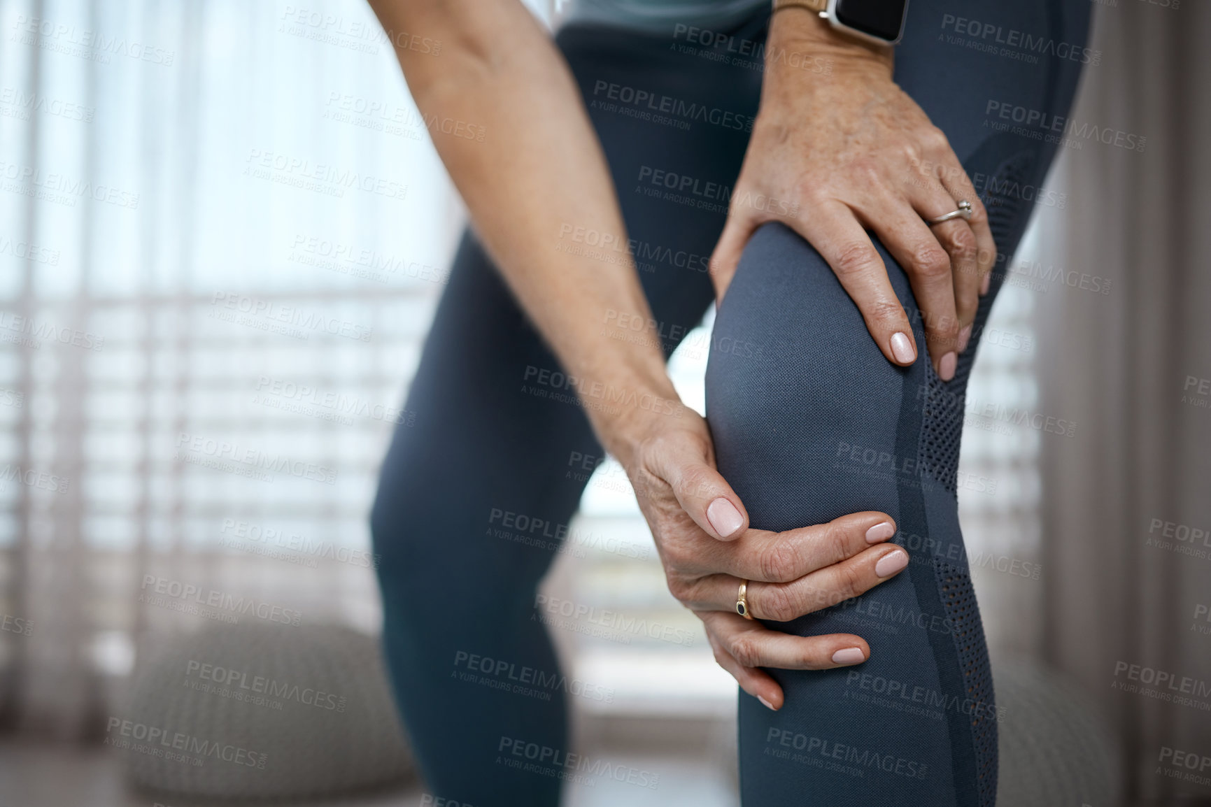 Buy stock photo Cropped closeup of an unrecognizable woman experiencing pain in her knee while exercising at home