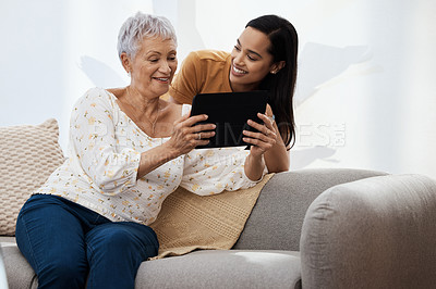 Buy stock photo Shot of a senior woman using a digital tablet with her daughter on the sofa at home