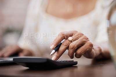 Buy stock photo Shot of an unrecognisable senior woman using a calculator while going through finances at home