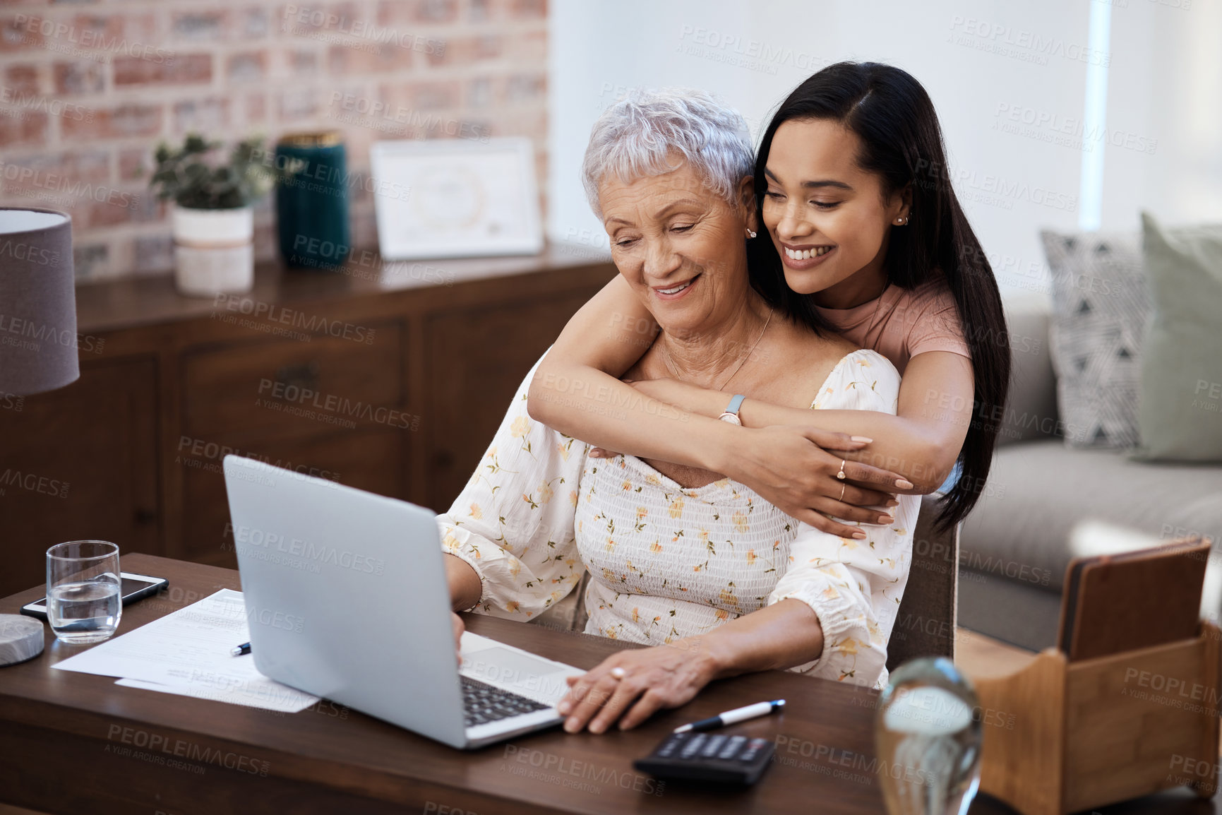 Buy stock photo Shot of a young woman using a laptop with her elderly mother while going through finances at home