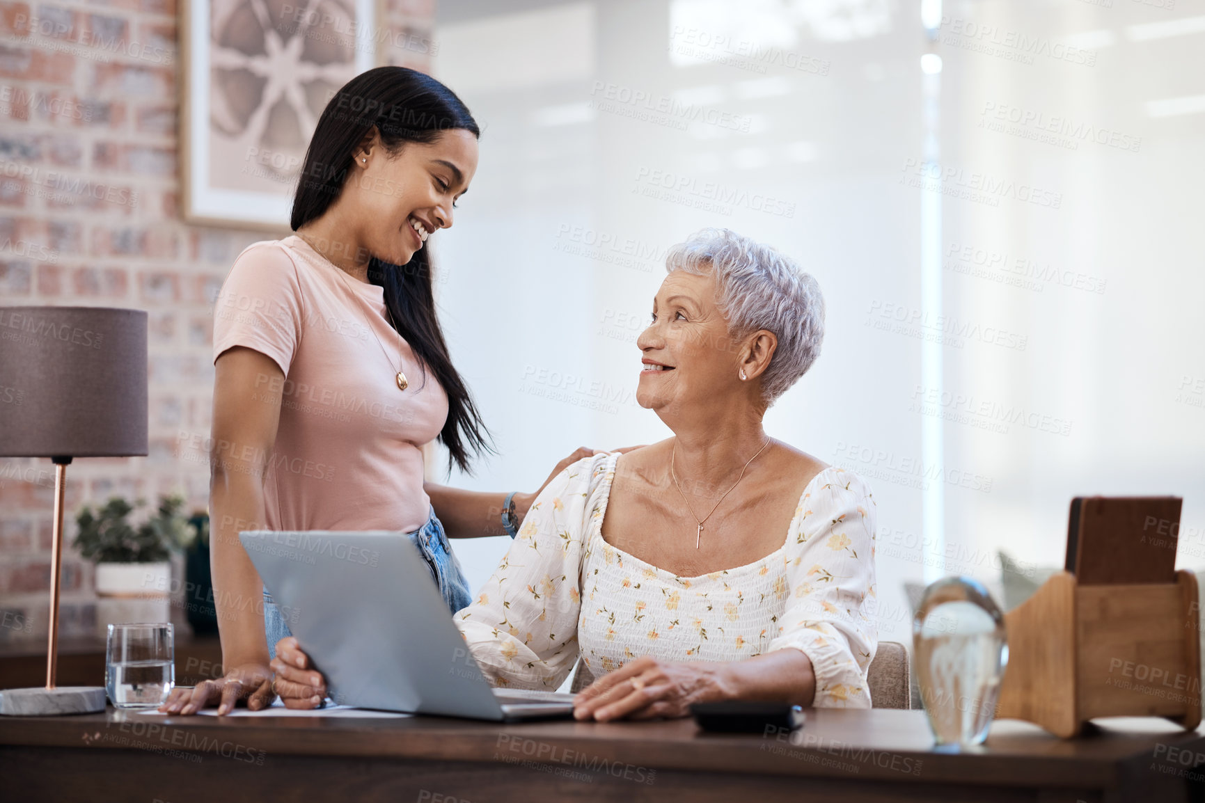 Buy stock photo Shot of a young woman using a laptop with her elderly mother while going through finances at home