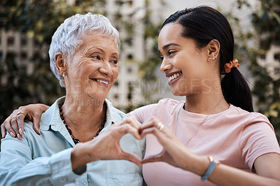 Buy stock photo Shot of a senior woman and her daughter making a heart shape with their hands in the garden at home
