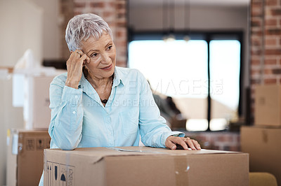 Buy stock photo Shot of a senior woman looking unhappy while moving house