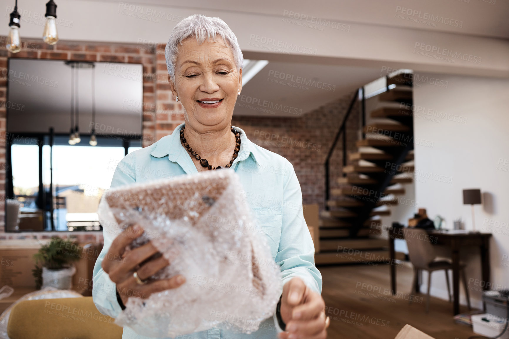 Buy stock photo Shot of a senior woman looking at a photograph while packing boxes on moving day