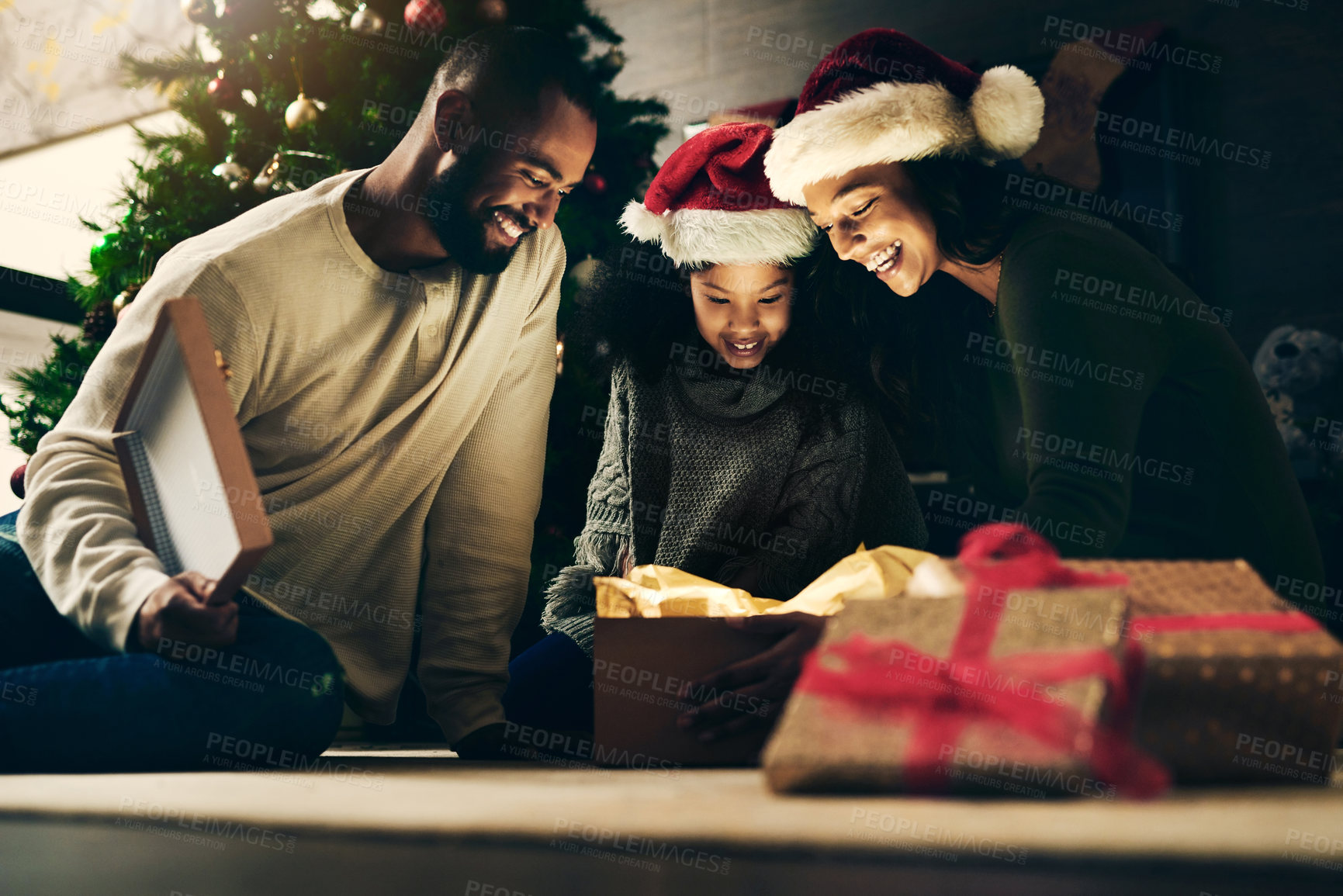 Buy stock photo Mother, father and child with gift for Christmas in celebration of a Christian winter holiday as a happy family. Night, mom and dad love giving young girl a surprise present to celebrate xmas at home