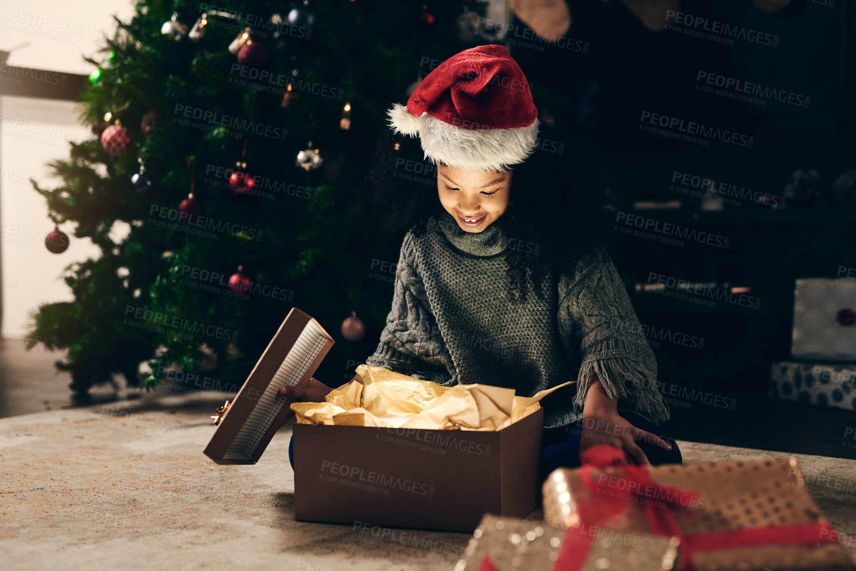 Buy stock photo Christmas, gift and girl opening box at night in home on holiday. Xmas spirit, happy and excited child or kid with smile, looking at glowing presents or gifts and enjoying December holidays in house.