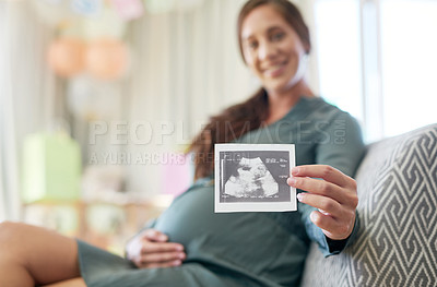 Buy stock photo Shot of a young mother to be holding an ultrasound of her unborn child