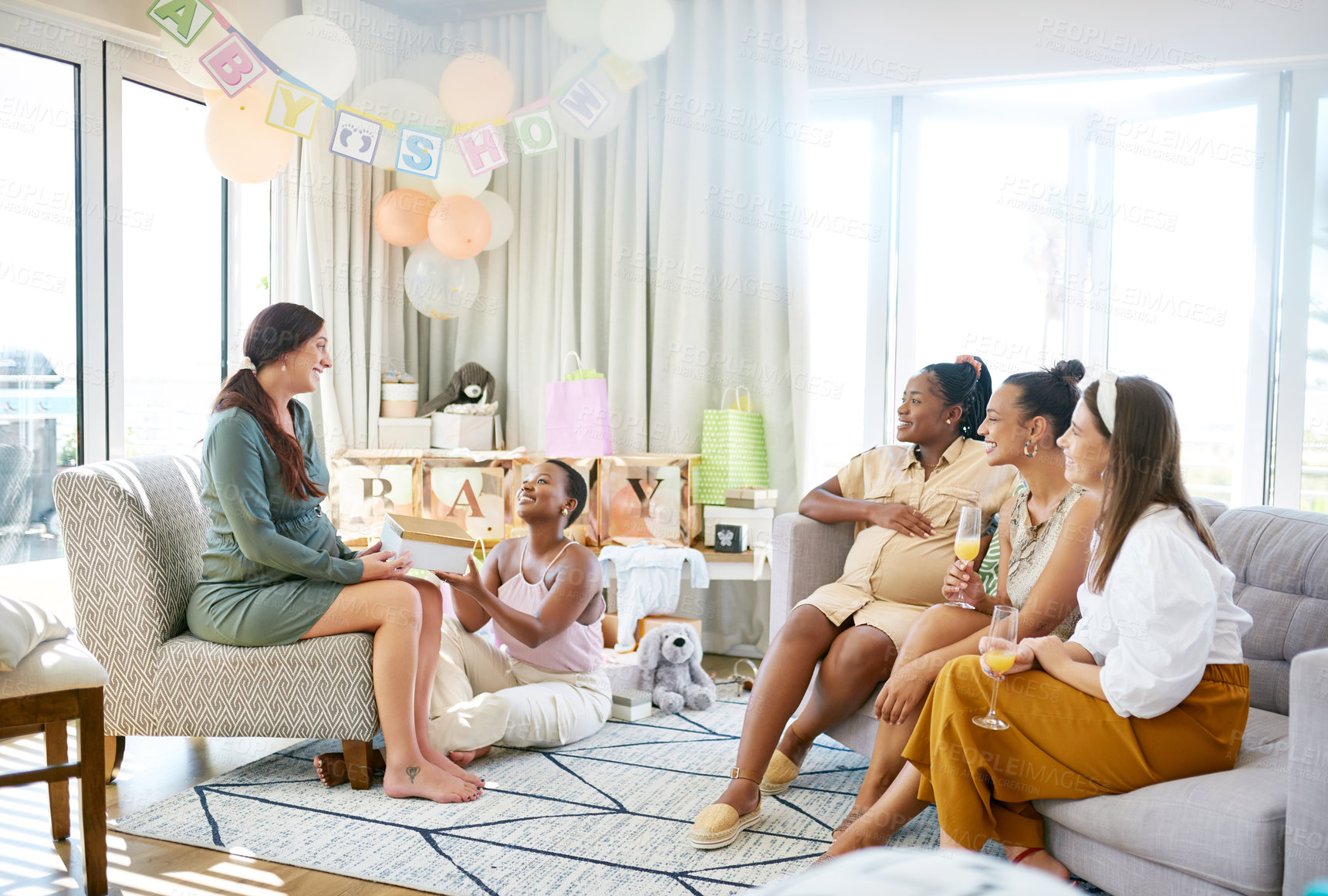 Buy stock photo Shot of a young mother opening a gift from her friends at her baby shower