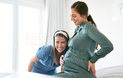 Buy stock photo Shot of a woman putting her ear to her friends baby bump