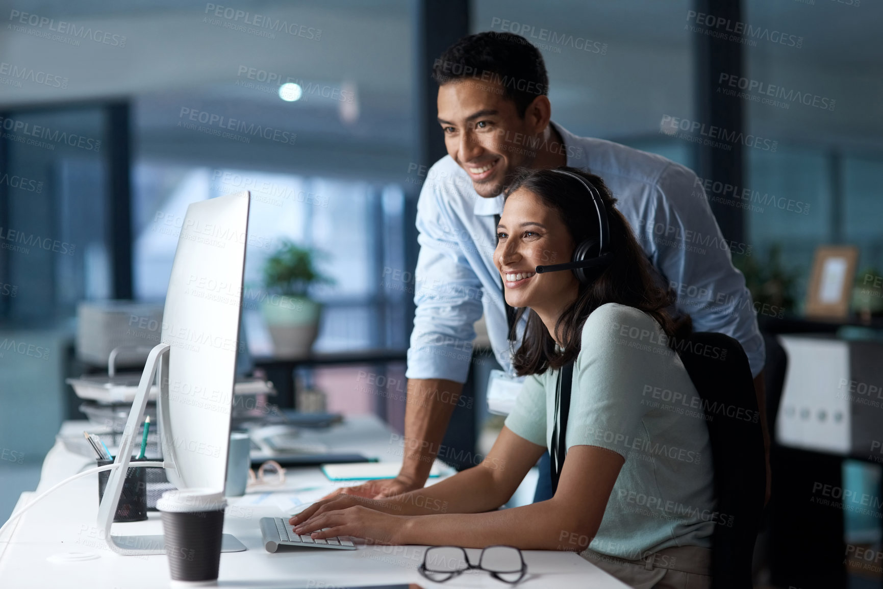 Buy stock photo Shot of a young man and woman using a computer while working in a call centre