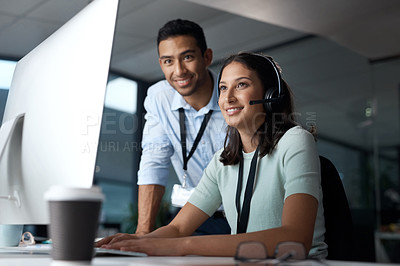 Buy stock photo Shot of a young man and woman using a computer while working in a call centre