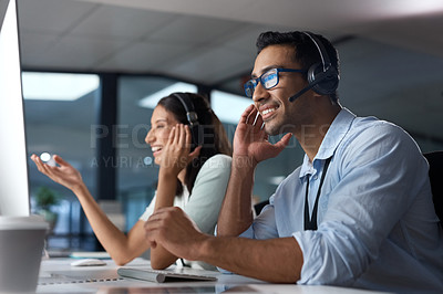 Buy stock photo Shot of a young man using a headset and computer in a modern office