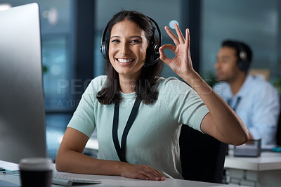 Buy stock photo Portrait of a young woman using a headset and showing an okay gesture in a modern office