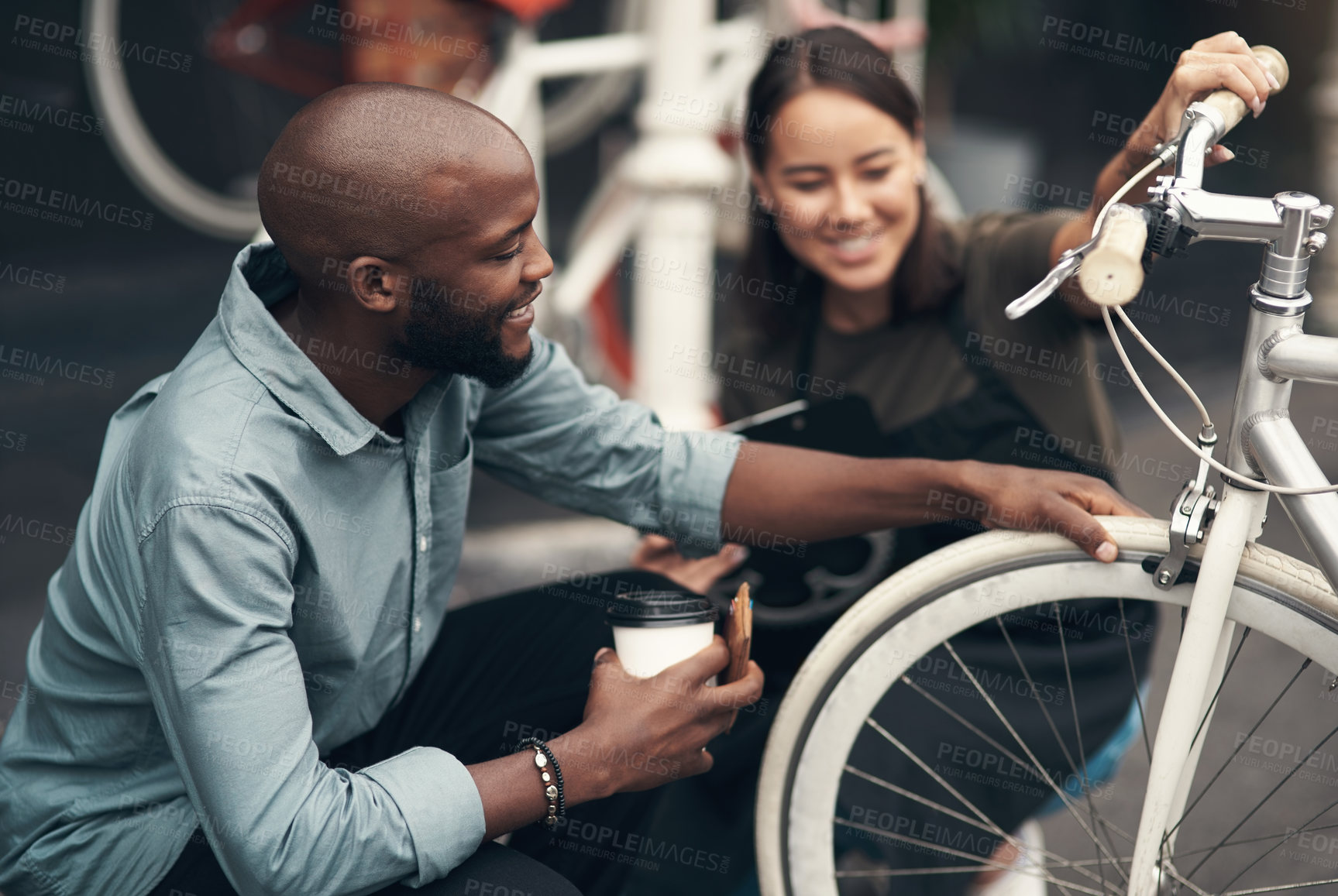 Buy stock photo Shot of an attractive young woman crouching outside her bicycle shop and assisting a customer