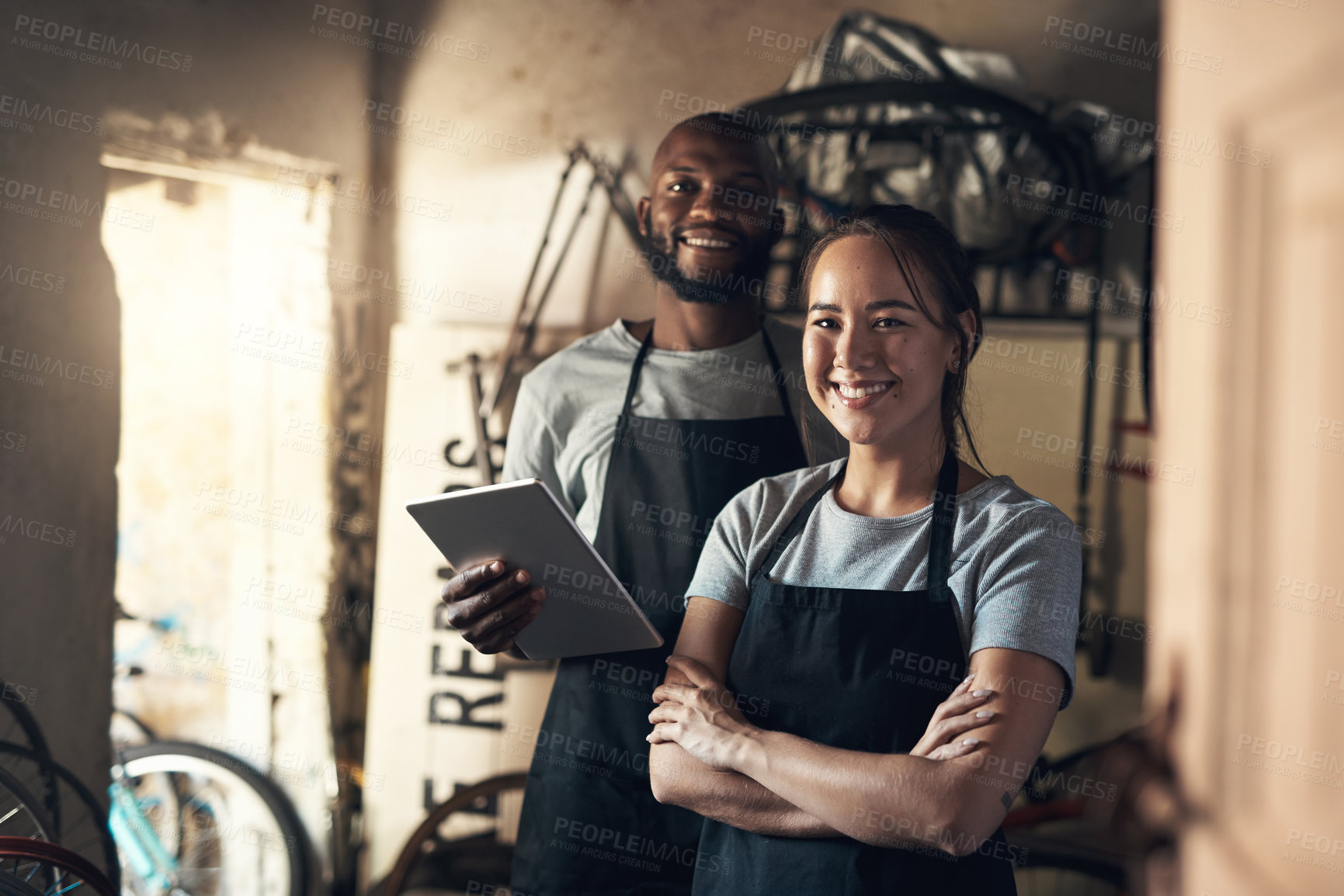 Buy stock photo Portrait of two young people working at a bicycle repair shop