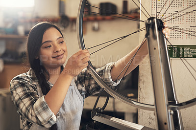 Buy stock photo Shot of a young woman working on a bike at a bicycle repair shop