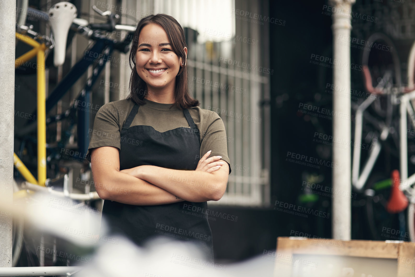Buy stock photo Shot of an attractive young woman standing outside her bicycle shop with her arms folded