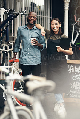 Buy stock photo Full length shot of two young business owners standing outside their bicycle shop during the day