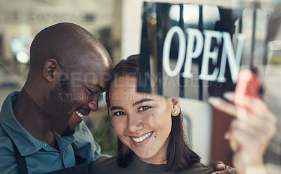 Buy stock photo Shot of a young couple standing together and turning the sign on the door to their bicycle shop