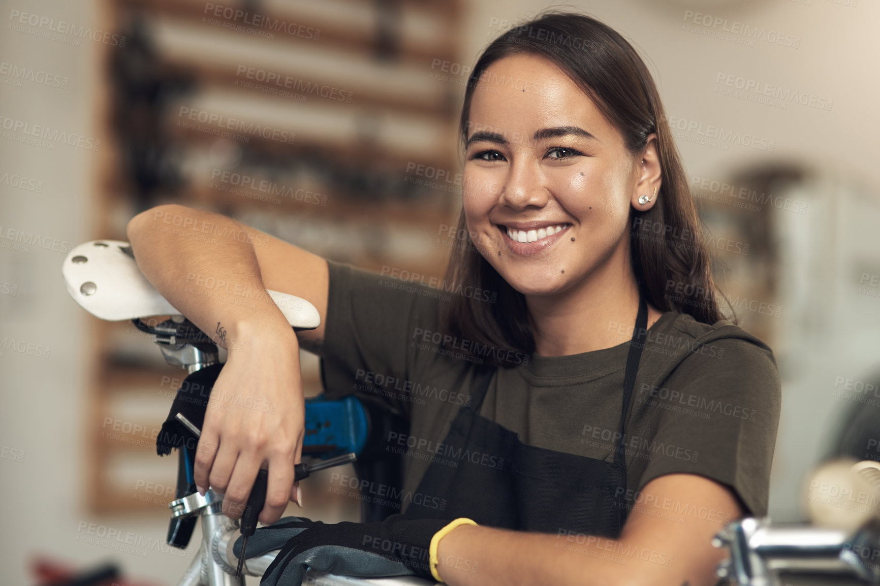 Buy stock photo Shot of an attractive young woman standing alone in her bicycle shop during the day