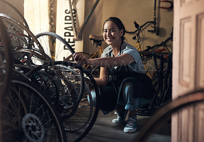 Buy stock photo Portrait of a young happy young woman fixing a bike at a bicycle repair shop