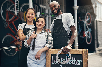 Buy stock photo Portrait of three young workers standing behind a bicycle repair sign outside