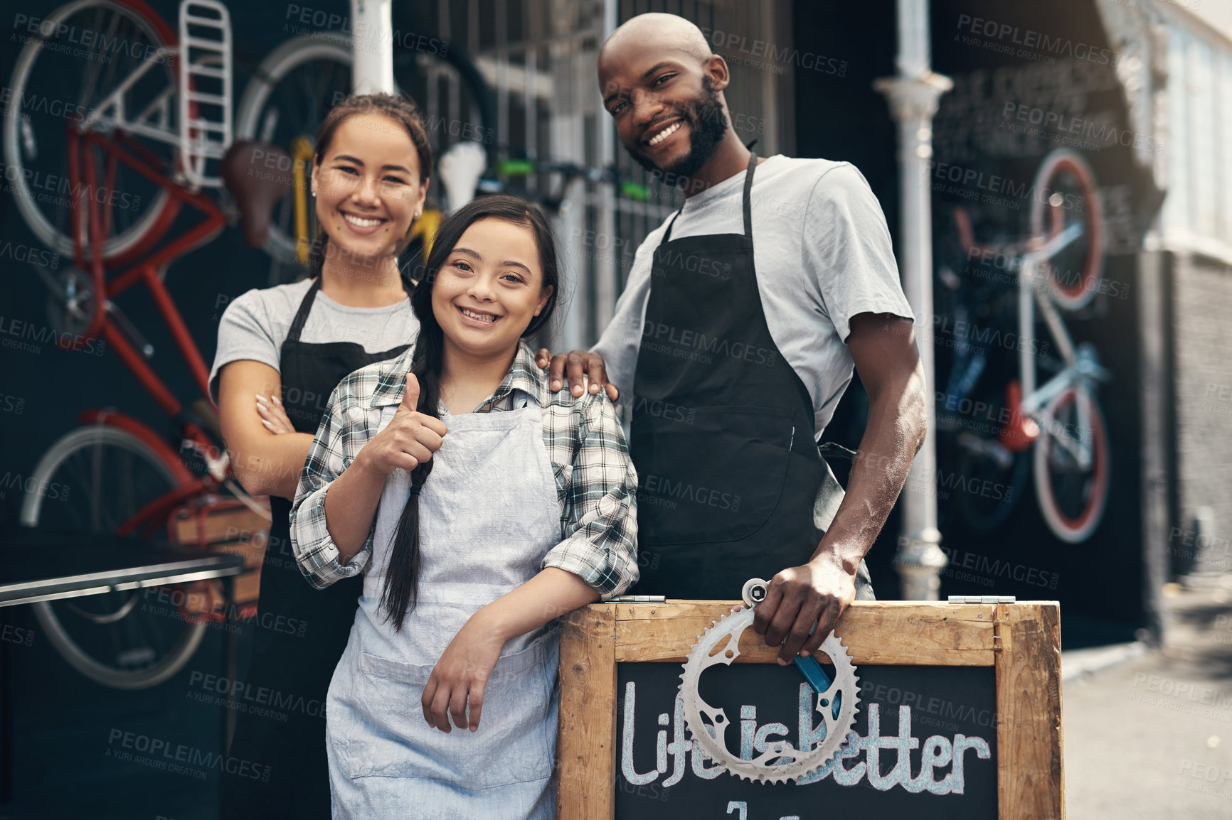 Buy stock photo Portrait of three young workers standing behind a bicycle repair sign outside