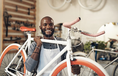 Buy stock photo Portrait of a young man lifting a bicycle up at work