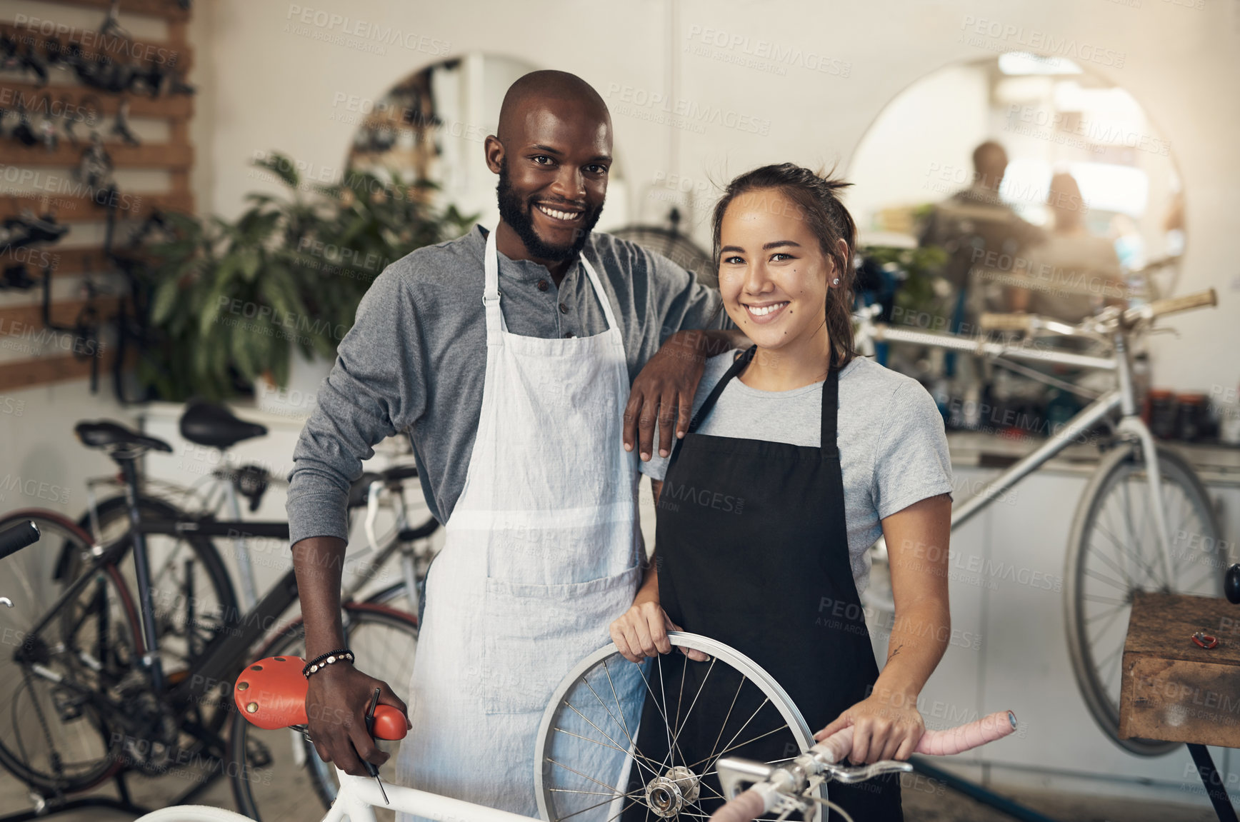 Buy stock photo Portrait of two colleagues fixing a bike at a bicycle repair shop