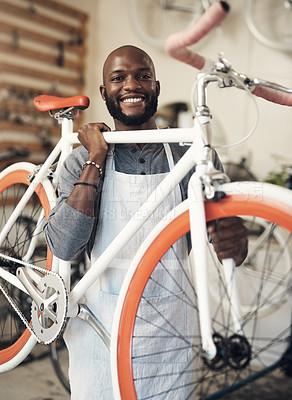 Buy stock photo Portrait of a young man lifting a bicycle up at work