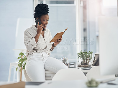 Buy stock photo Shot of a young businesswoman using her smartphone to make phone calls at the office while reading from her notebook